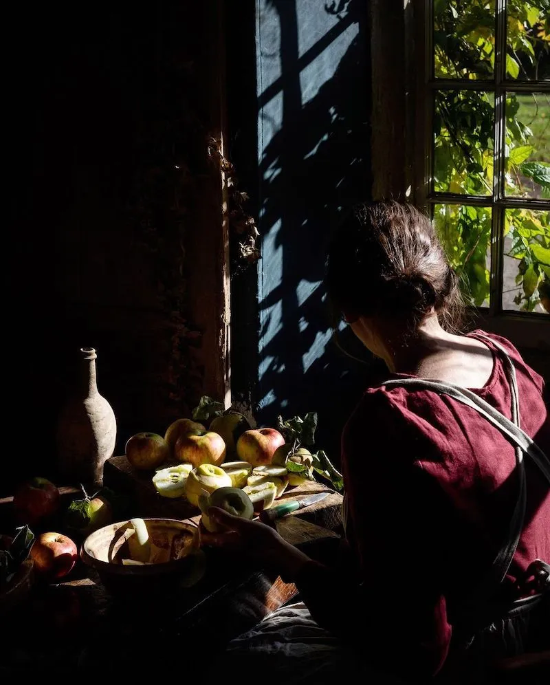 Photography of a woman in front of a table with fruits on it, taken by Aimee Twigger