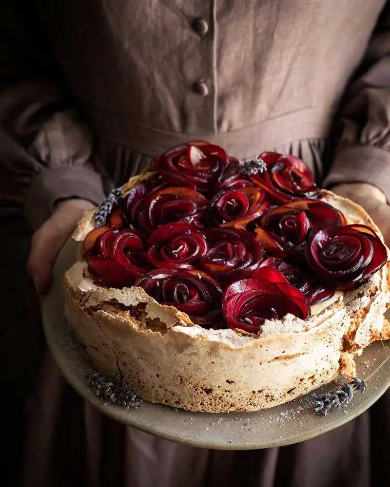 Photography of someone holding a cake with red roses made out of food on the top