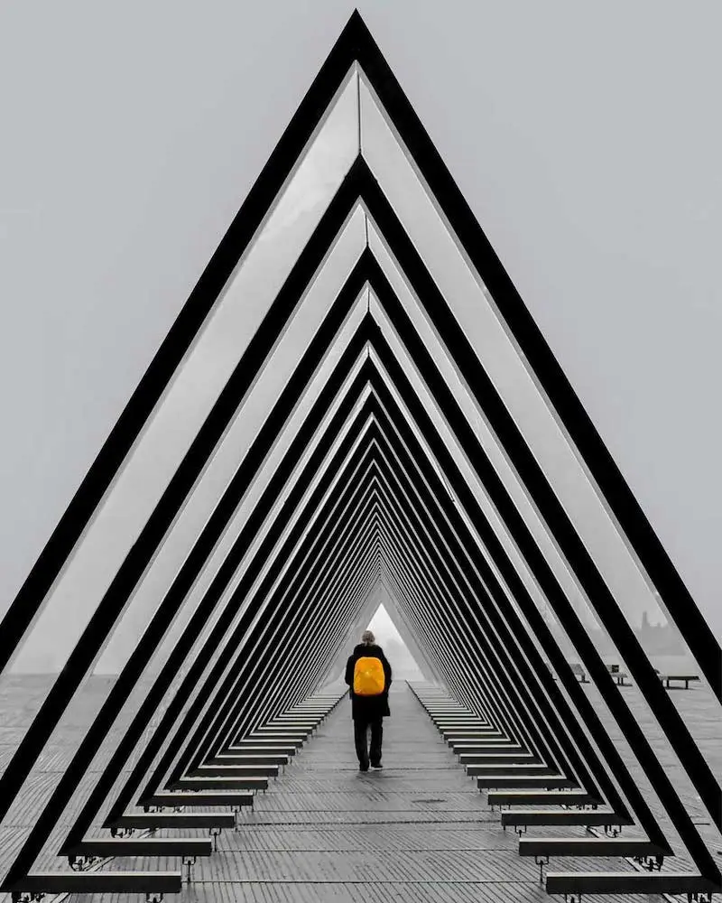 Photography of a pyramidal structure with someone walking inside of it, taken by Ash Camas, contemporary architecture photographer